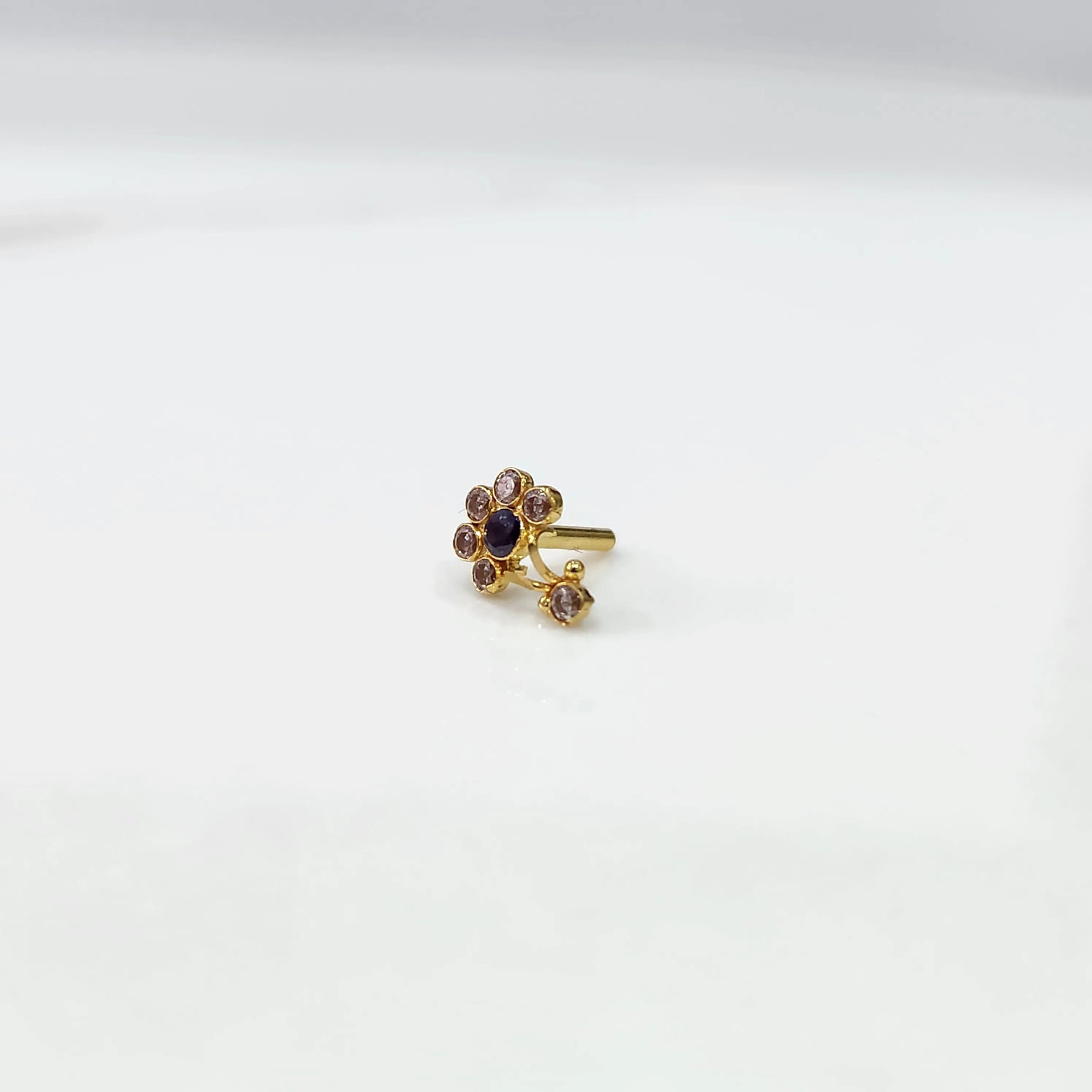 Front view of gold ring featuring clear floral gemstones with blue center and drop pendant