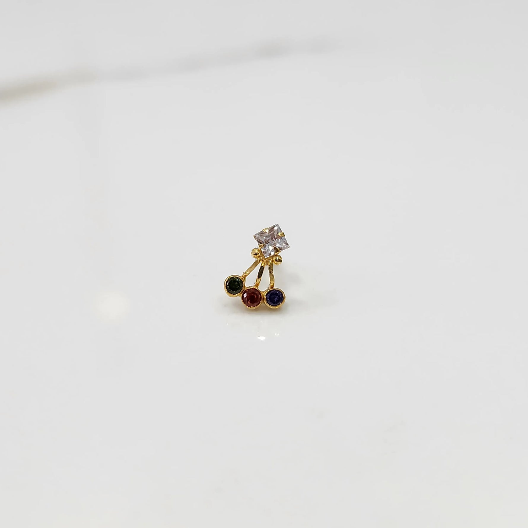 Antique-style gold ring featuring a square stone and hanging colored gems
