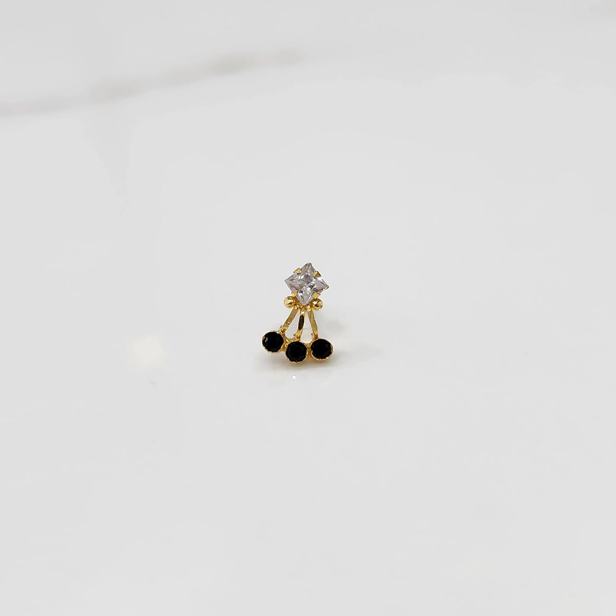 Antique-style gold ring featuring a square stone and hanging black gems, side angle