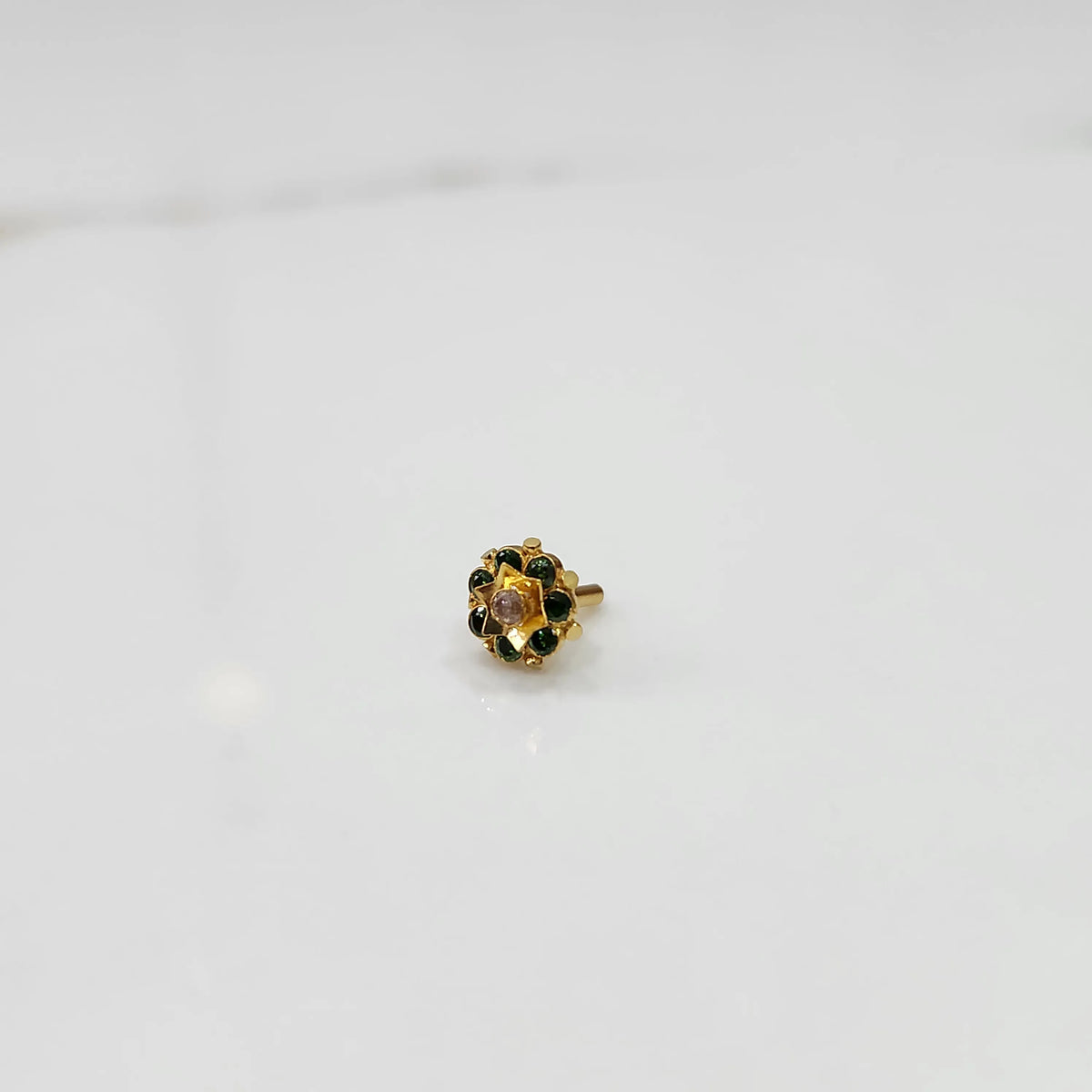Side angle of gold ring with green gemstone petals and gold star center