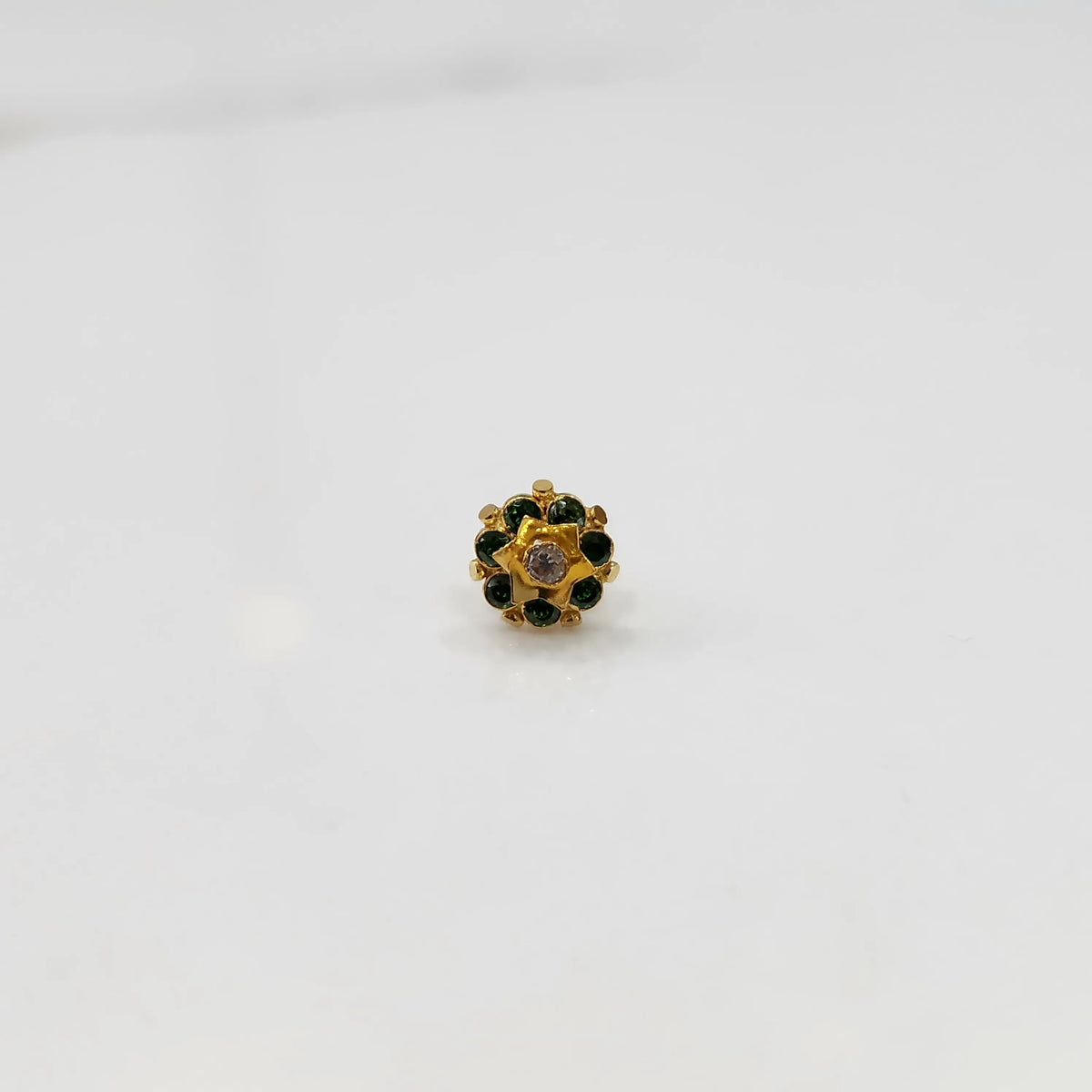 Top-down view of gold ring with green gemstone petals and star center
