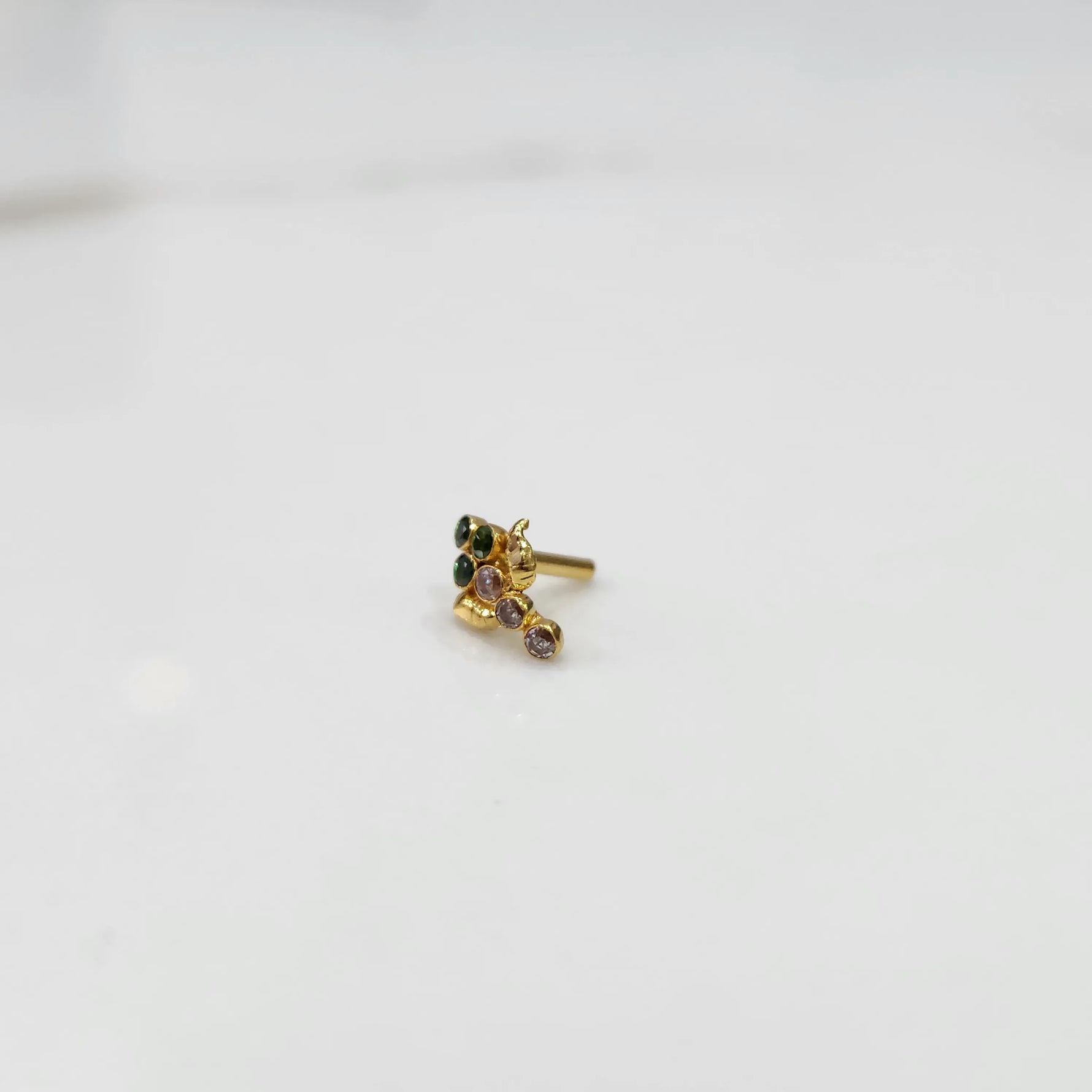 Side view of gold ring featuring green and purple gemstone cluster with leaf accent