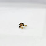 Front view of gold ring featuring black floral gemstones with clear center and drop pendant