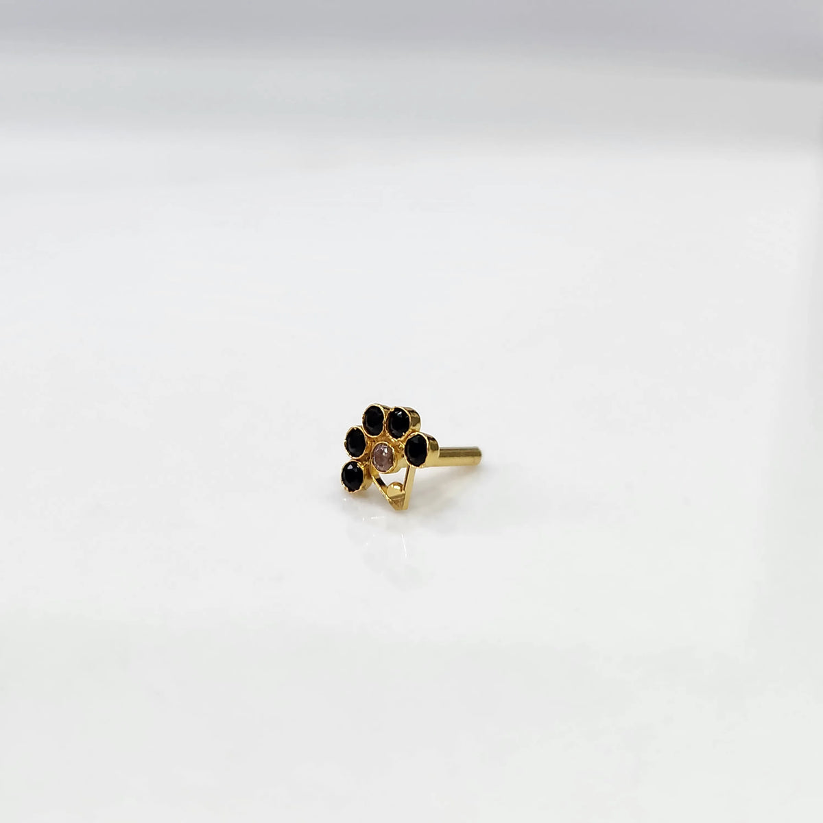 Front view of gold ring featuring black floral gemstones with clear center and drop pendant