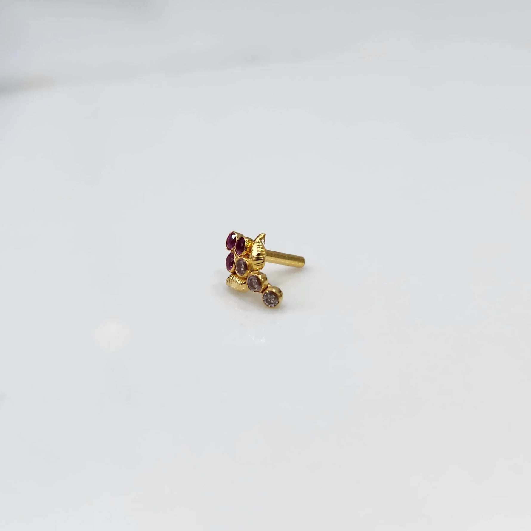 Side view of gold ring featuring red gemstone cluster with leaf accent