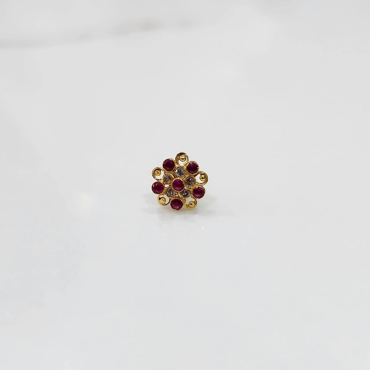 Front view of gold ring with layered red and clear gemstone petals