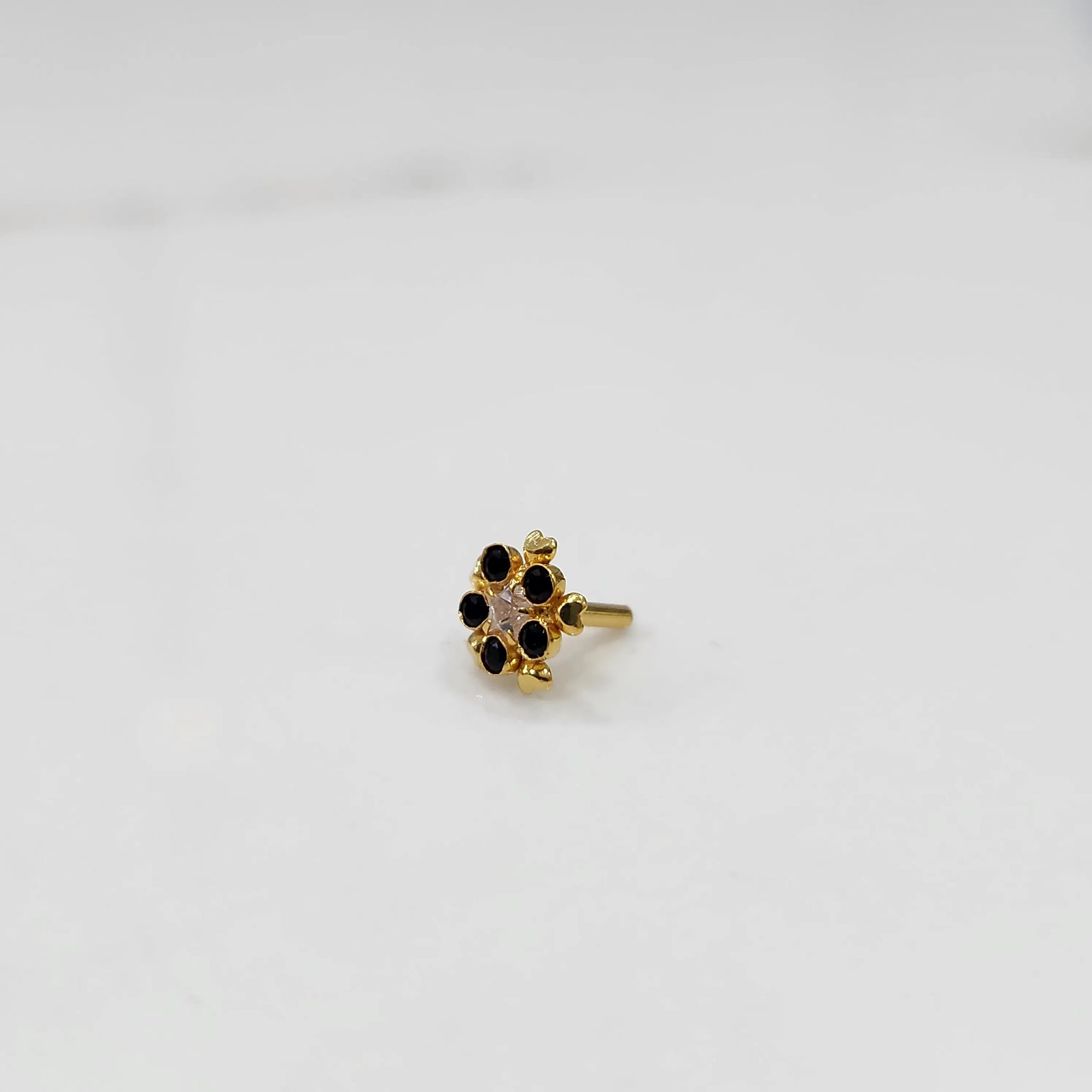 Black onyx flower cluster nose stud with gold petal design, jewelry photography