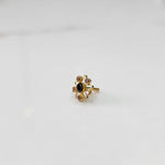 A gold nose pin shaped like a star with an oval black center stone and light pink and champagne accent stones