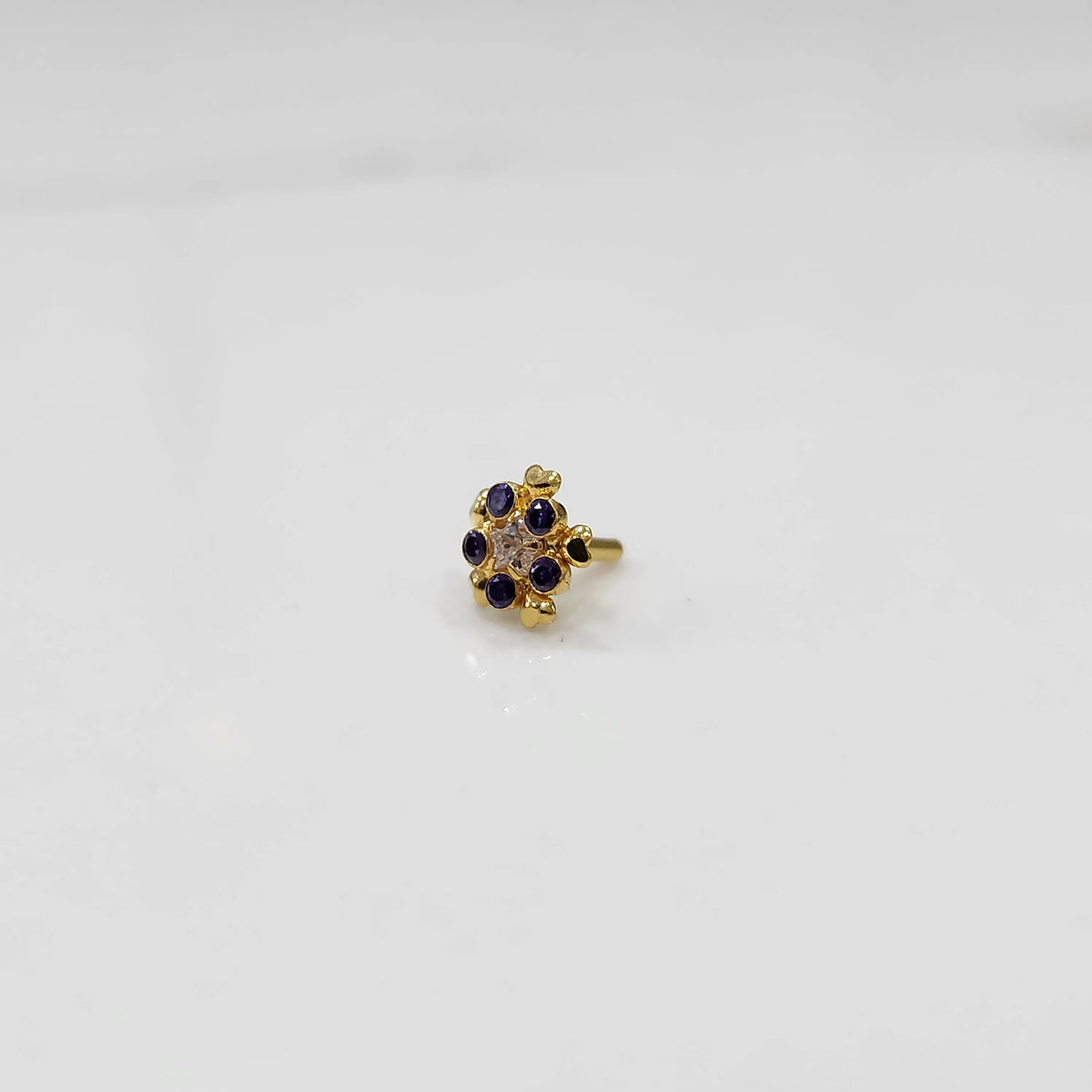 Sapphire flower cluster nose stud with gold heart setting, jewelry photography