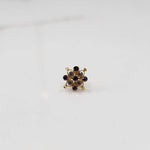 A gold nose pin shaped like a flower, set with blue sapphire-toned and clear crystal stones