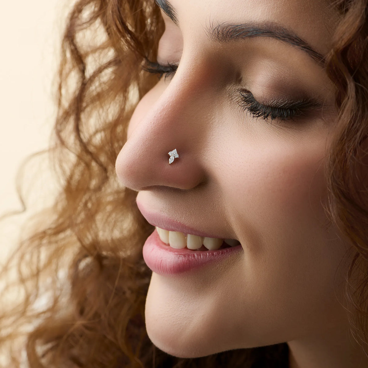 Close-up of woman wearing a silver nose stud with a bowtie-shaped diamond design
