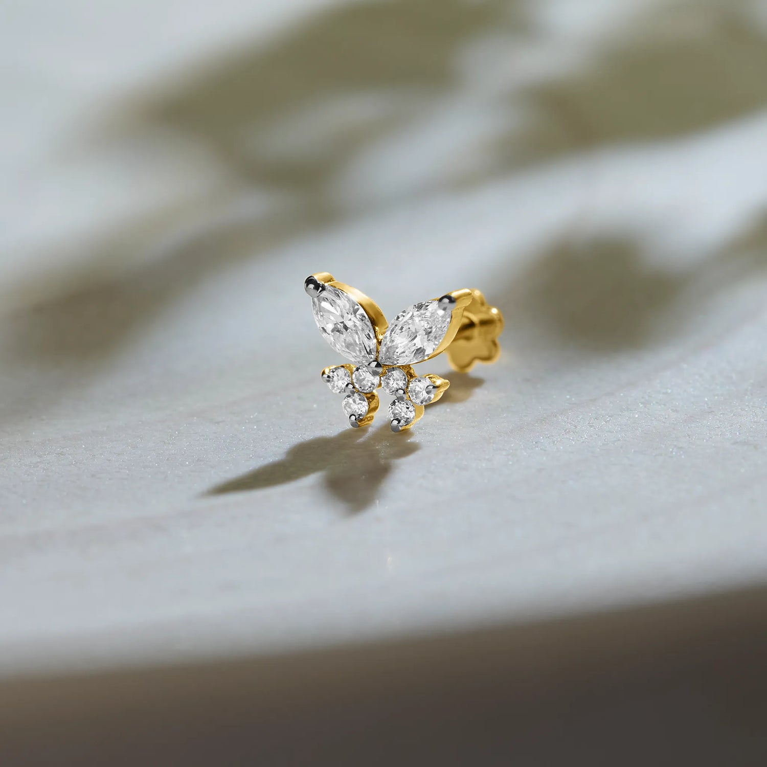 Nose pin lab grown diamond with butterfly shaped diamond cluster in gold on soft background