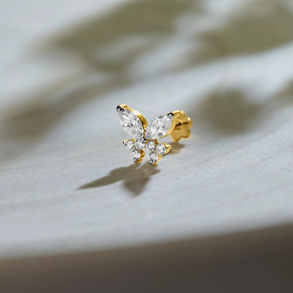 Nose pin lab grown diamond with butterfly shaped diamond cluster in gold on soft background