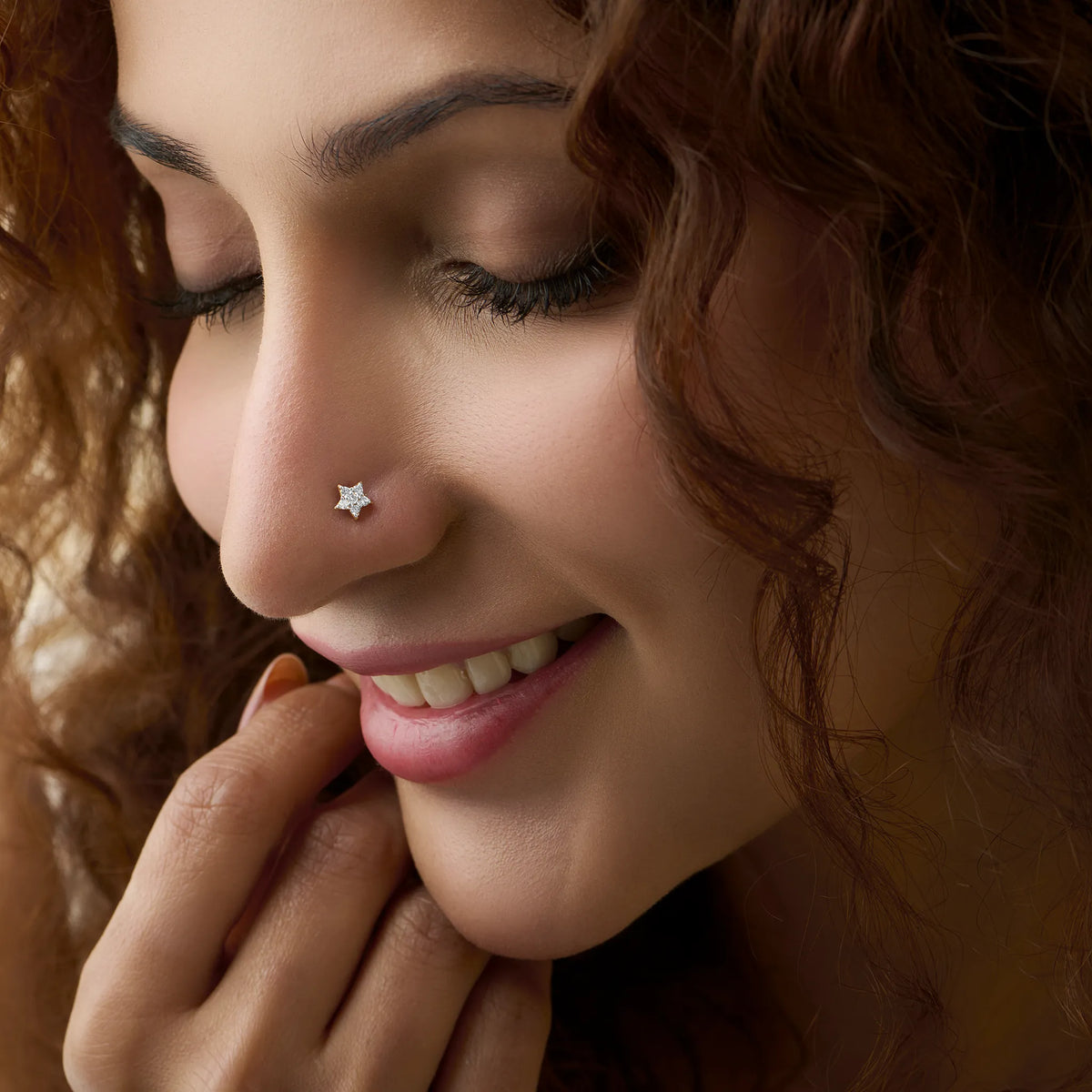 Five-point star nose stud worn by a smiling woman, close-up beauty shot