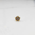 Product shot of a gold nose stud with clear gemstone flower and heart petal design