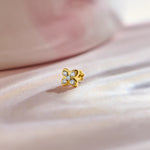 Flower nose pin gold with cute four-petal floral design featuring sparkling stones set in a polished gold base on a soft pink satin background