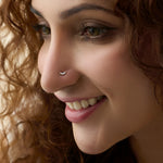 Close-up of woman wearing a nose stud with a curved diamond bar design
