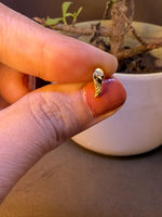 Curved leaf-shaped gold nose pin with ridged texture, held between fingertips