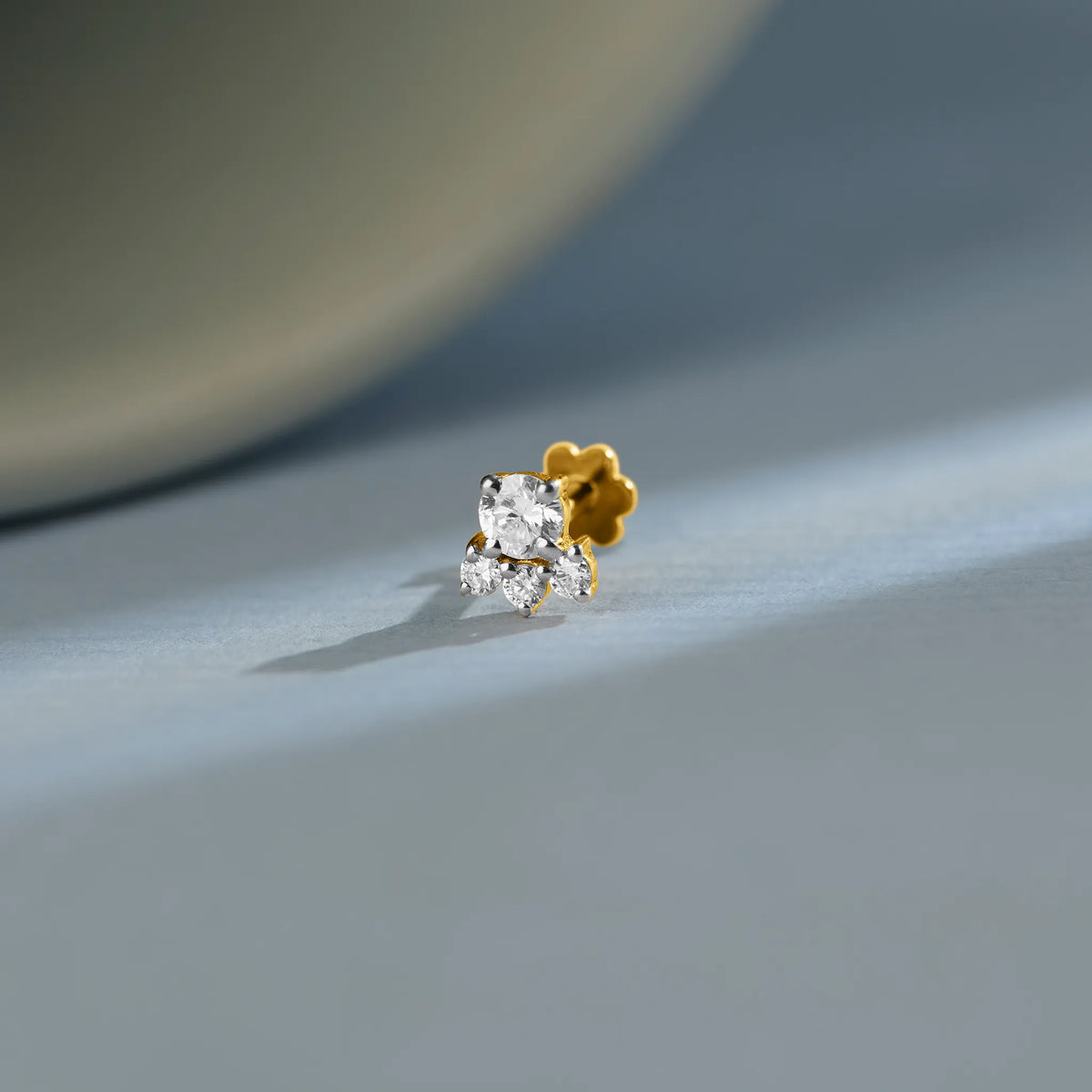 Trending gold nose pin with floral diamond cluster design on soft blue background