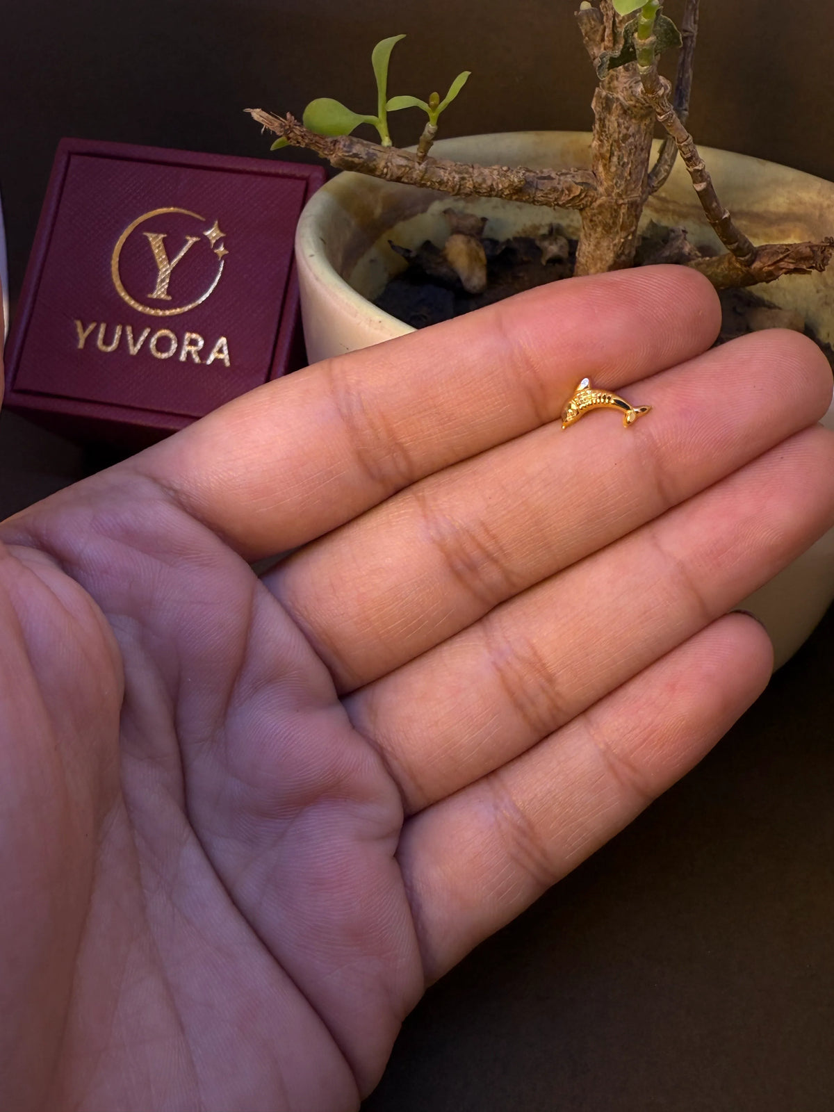 Dolphin-shaped gold nose pin, small and delicate, held in hand