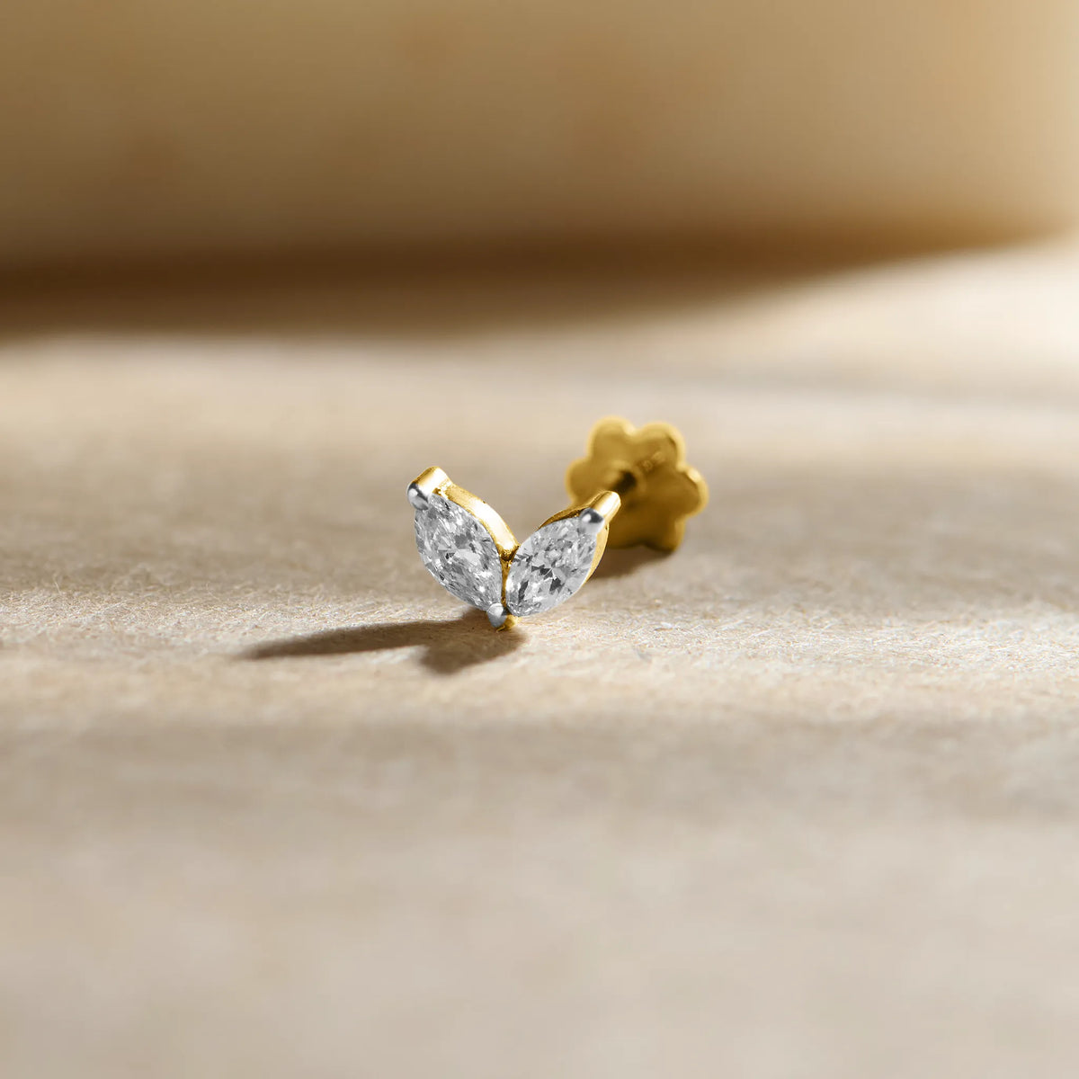 New nose pin design gold with elegant leaf-inspired twin stone pattern set in a polished gold base on a soft neutral background