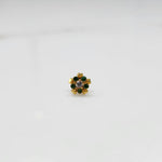 Product shot of a gold nose stud with emerald green gemstone flower and heart petal design