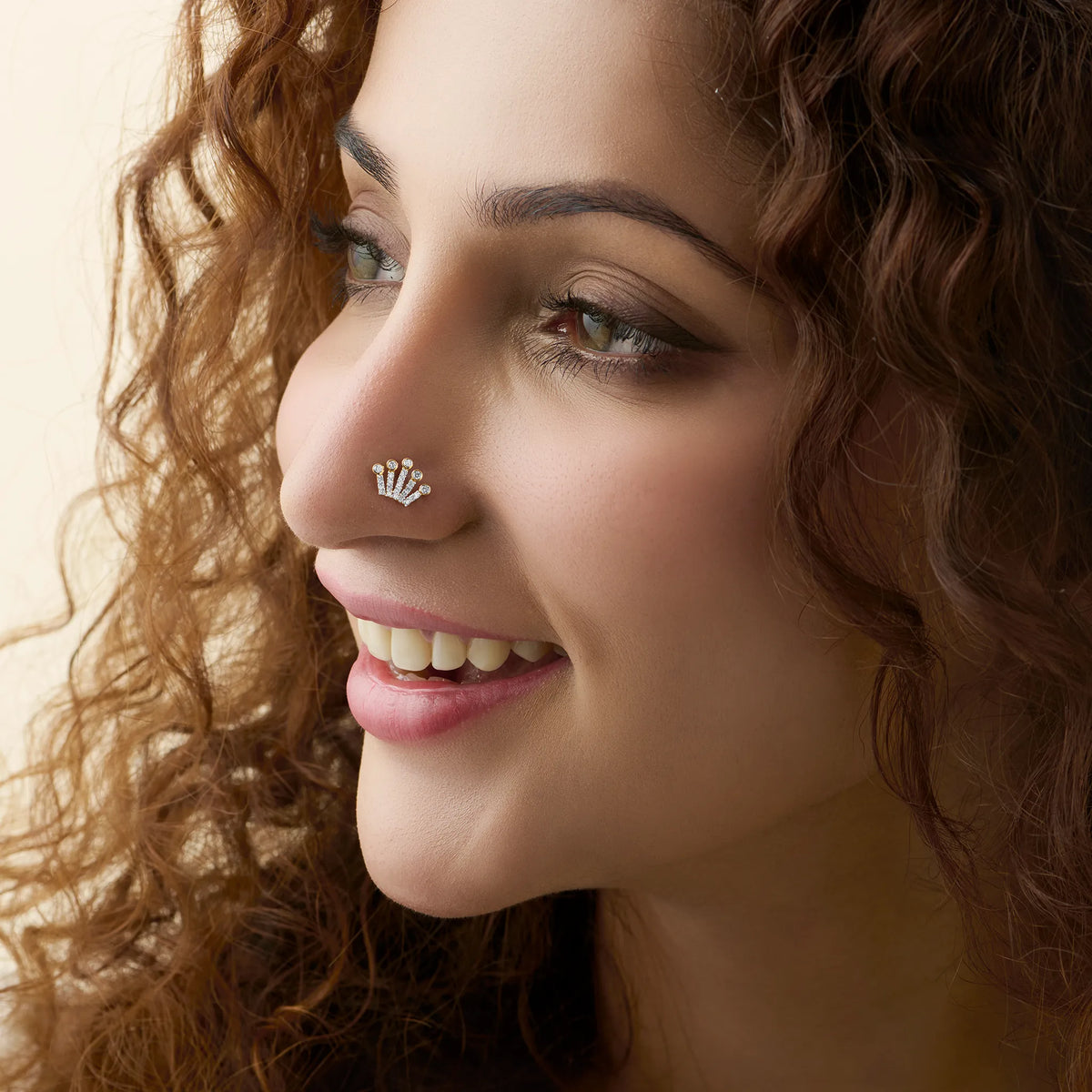 Fan-shaped diamond nose stud worn by a smiling woman, close-up beauty shot