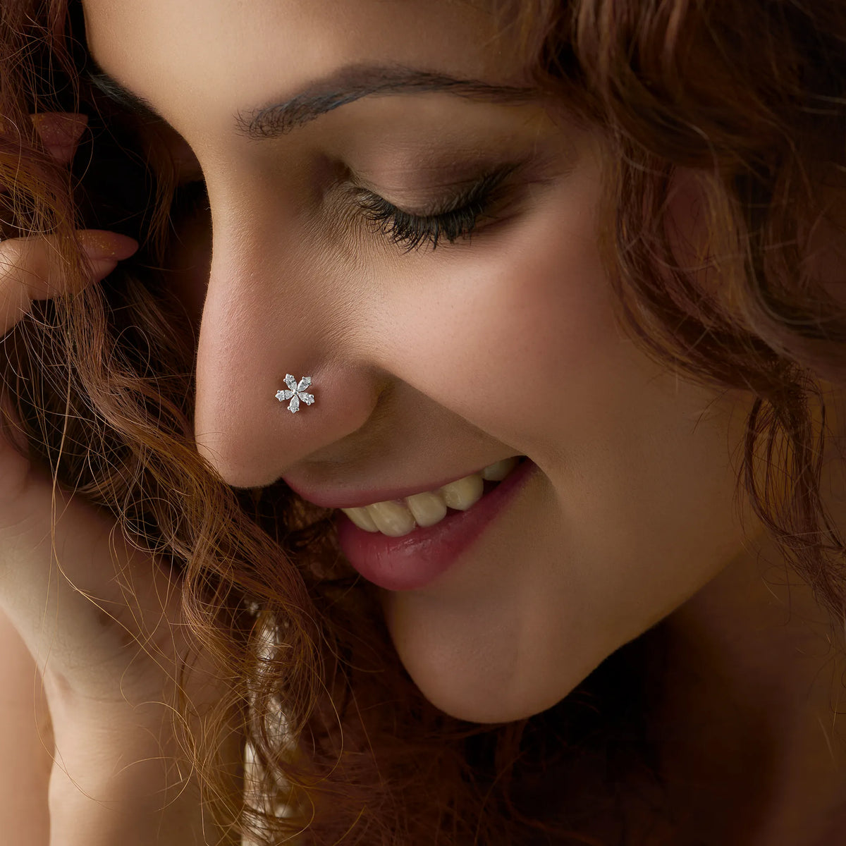 Close-up of woman wearing a nose stud with a snowflake-shaped diamond design