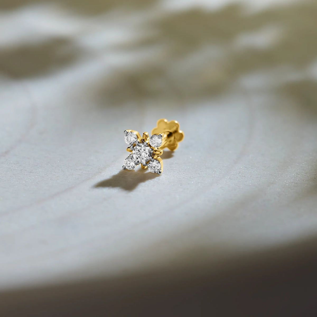 Flower gold nose pin with sparkling diamond petals on soft background