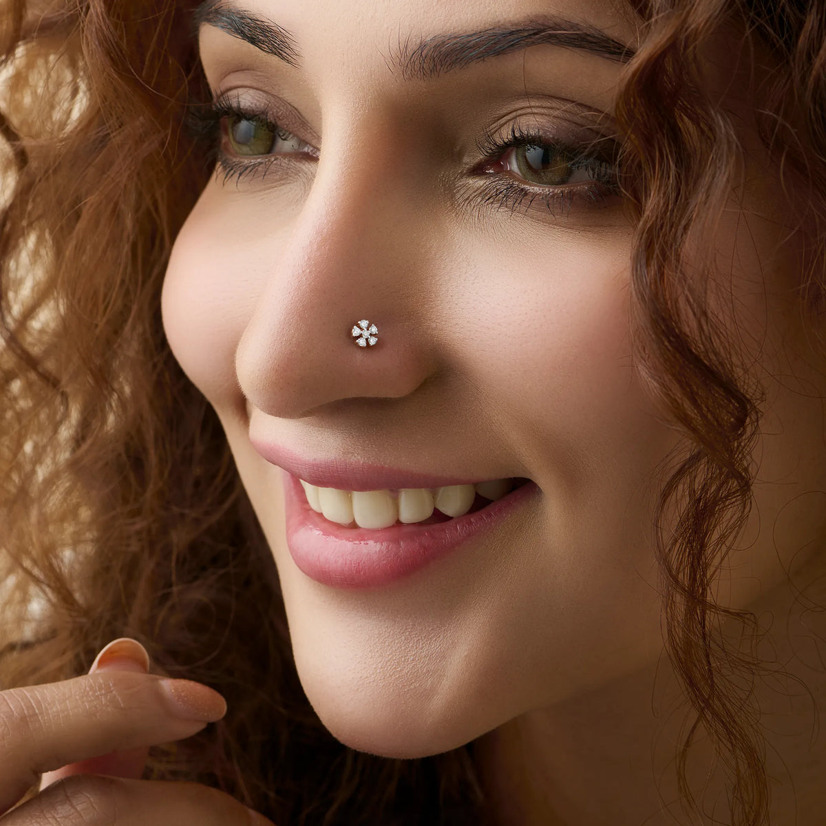 Close-up of woman wearing a nose stud with a pinwheel flower diamond design