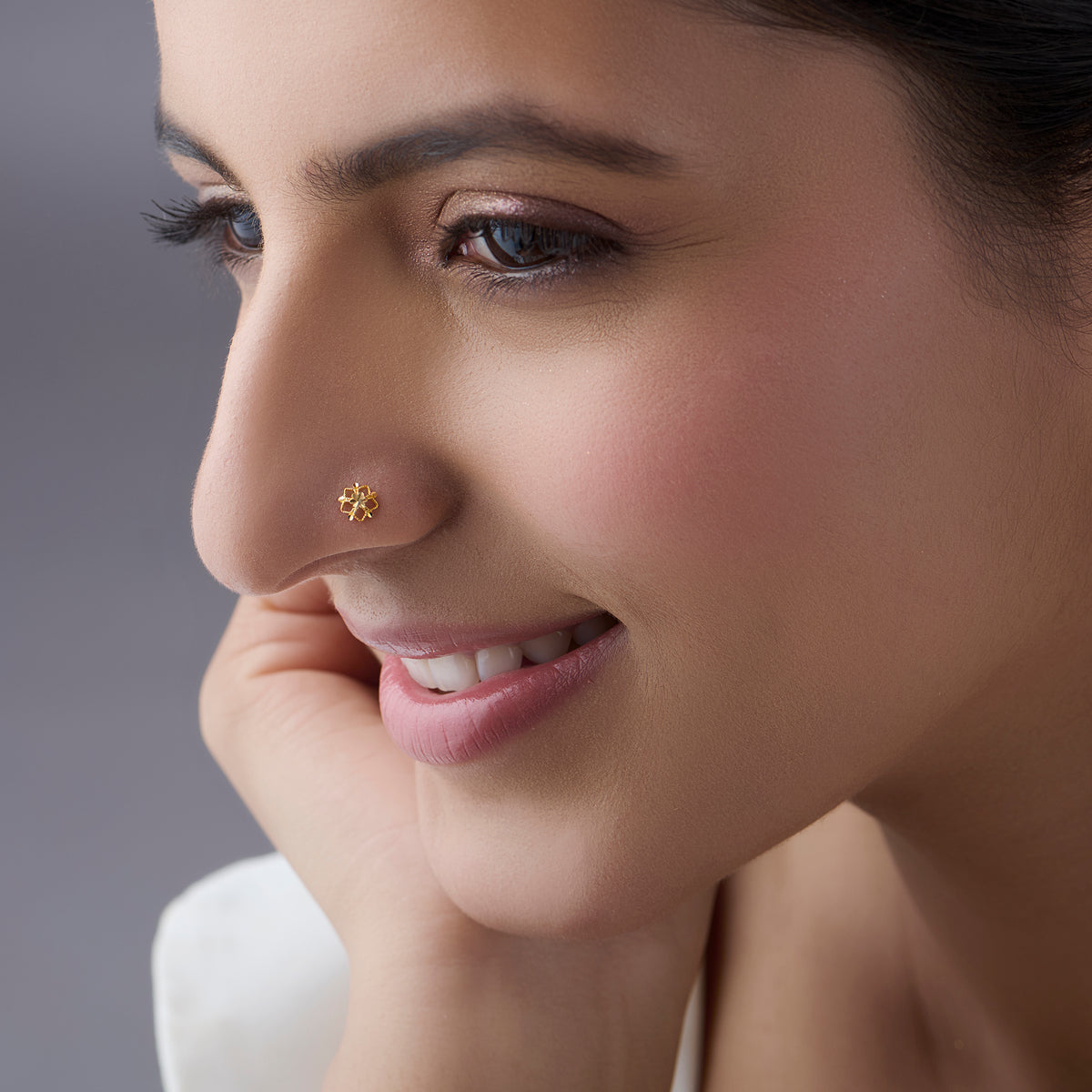 Side profile of a woman wearing a small floral gold nose pin