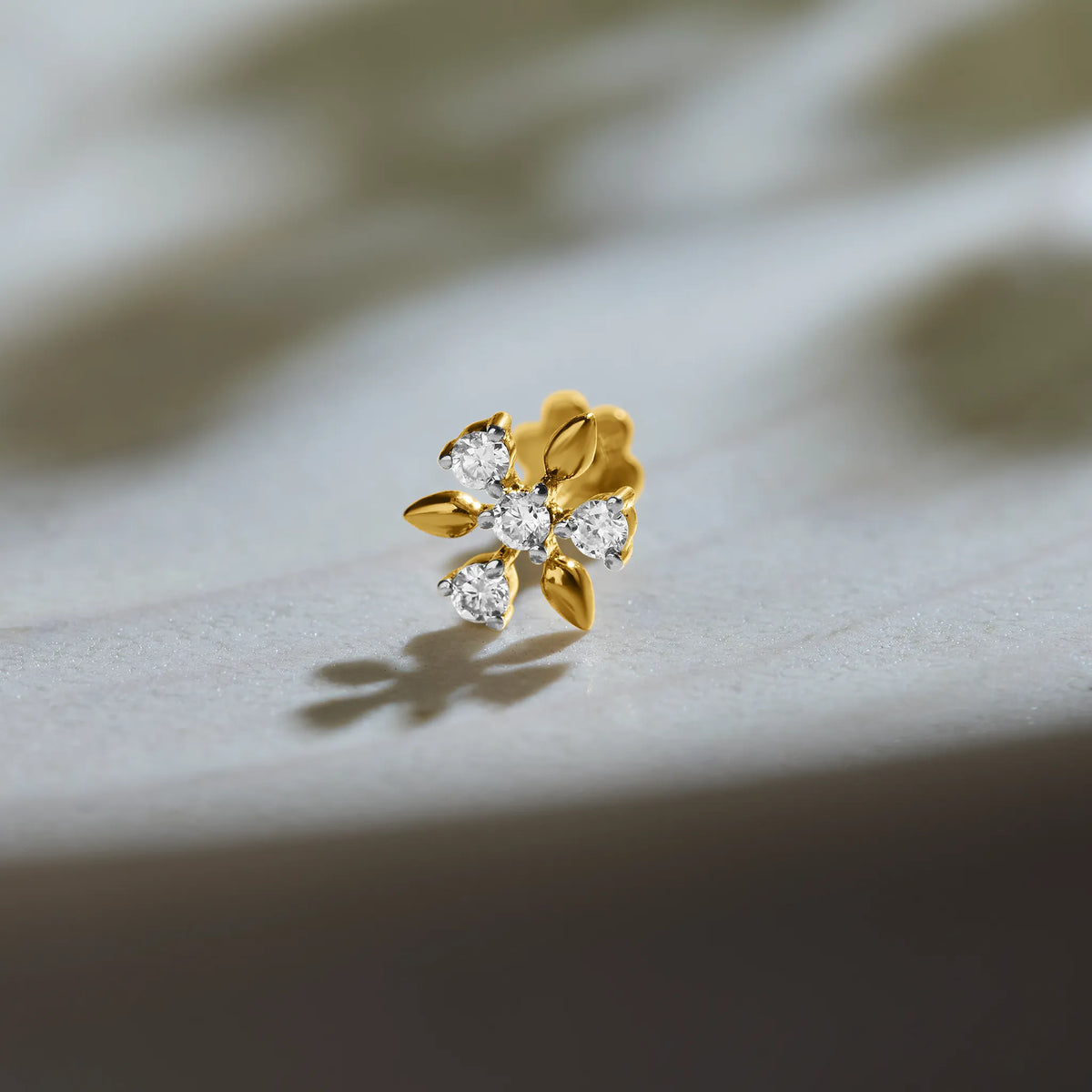 Flower-shaped diamond stud earring with gold leaf accents