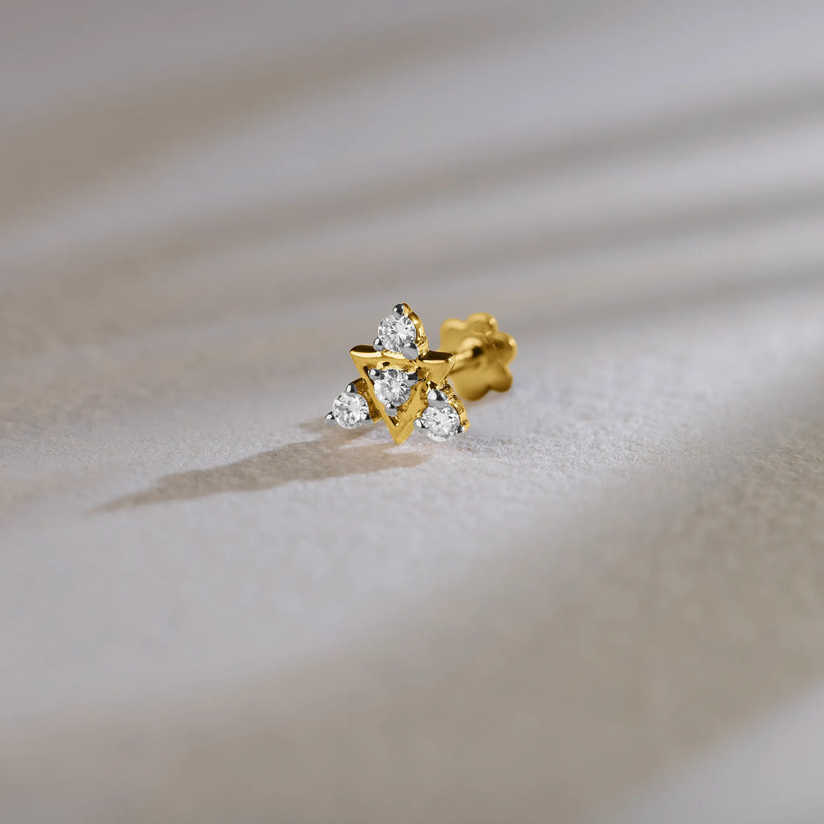 Traditional gold nose pin with floral diamond design on soft background