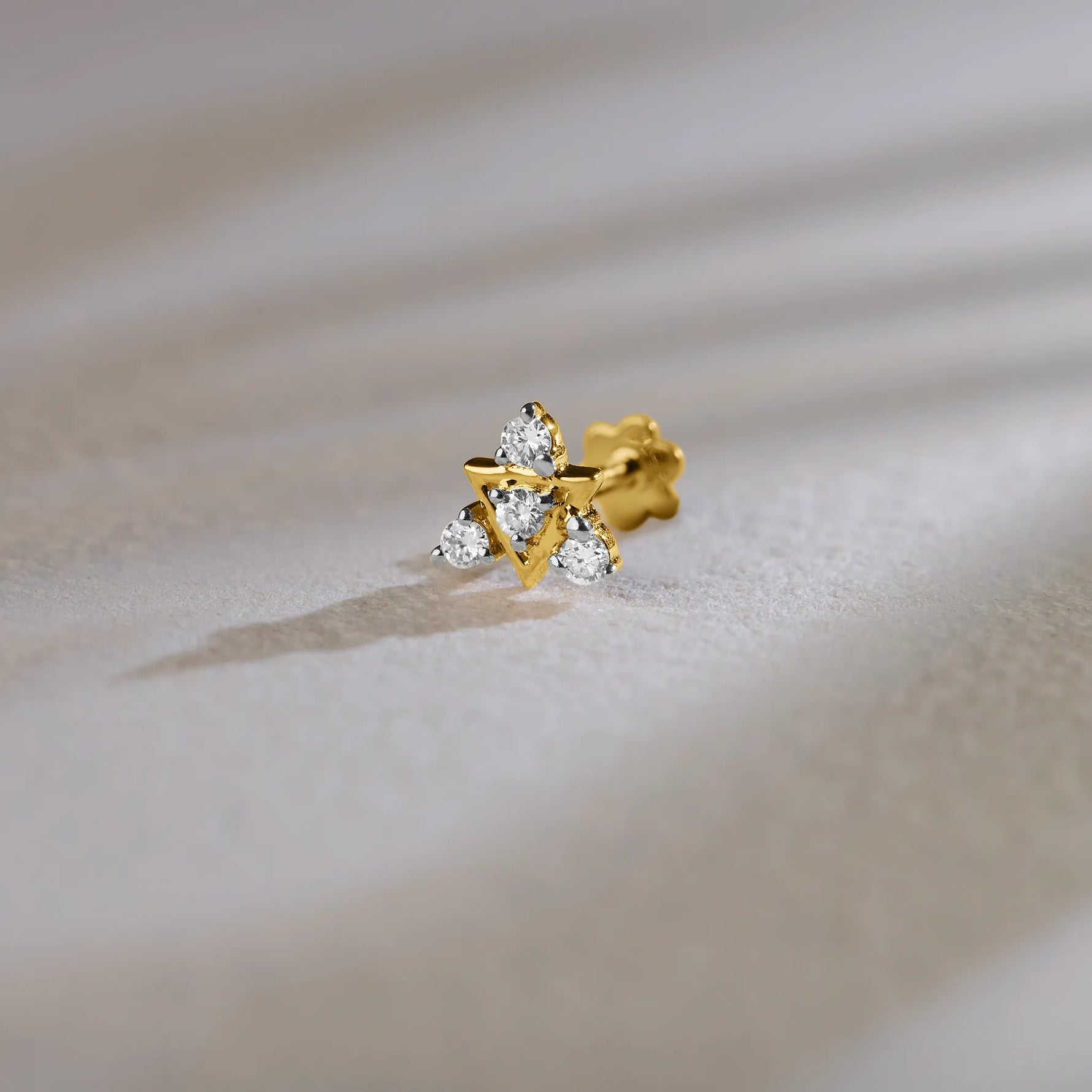 Traditional gold nose pin with floral diamond design on soft background