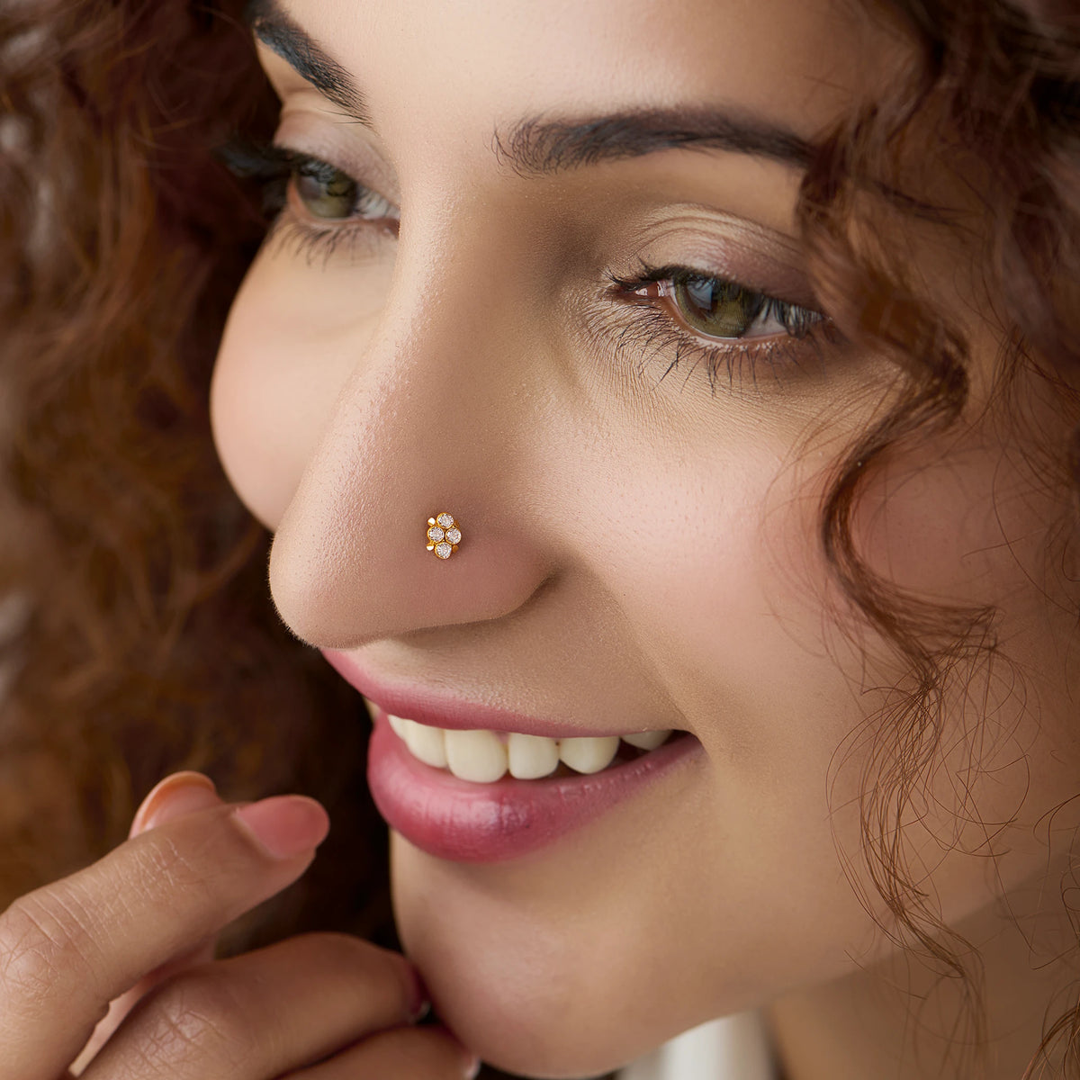 Woman wearing gold 4-petal nose pin with white stones