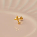 Gold airplane-shaped nose stud on beige background