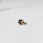 Front view of gold nose pin with black gemstone cluster and clear drop-style stone accent on white background