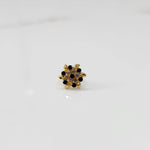 Front view of gold statement ring with black and clear gemstones in leaf-patterned cluster design