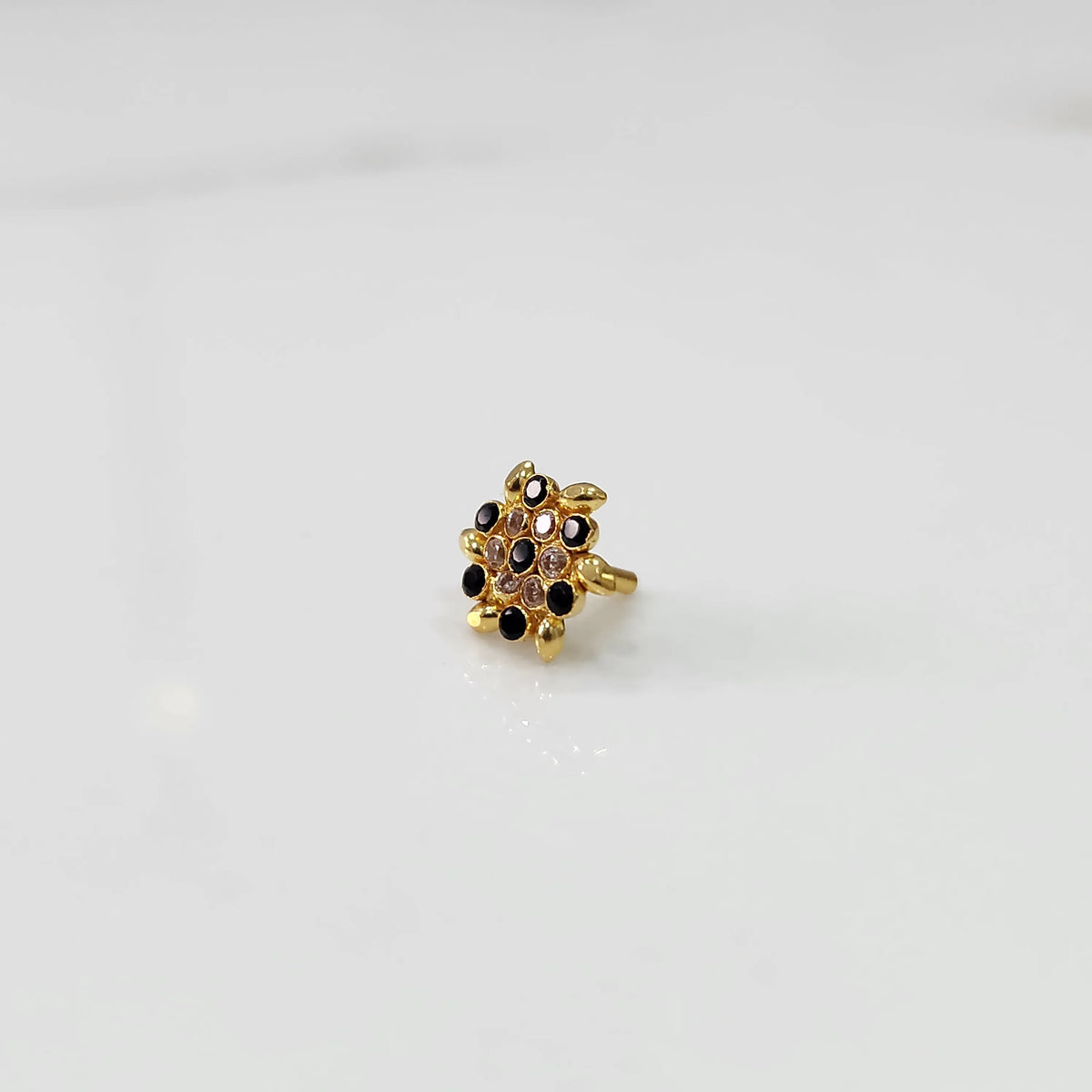 Gold statement ring with black and clear gemstones in leaf-patterned cluster design