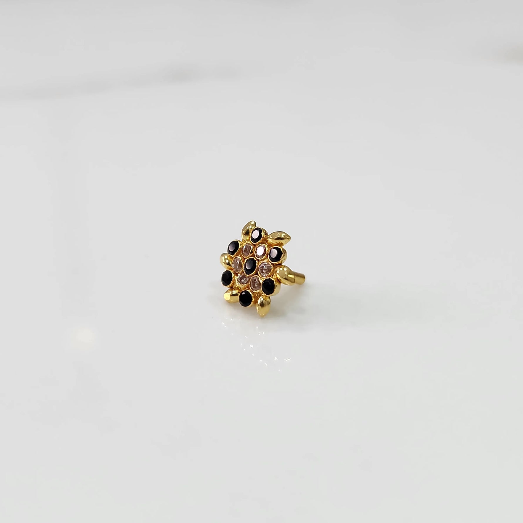 Gold statement ring with black and clear gemstones in leaf-patterned cluster design