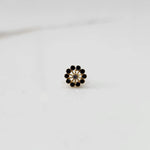 Front view of large gold nose pin with black gemstone flower design on white background
