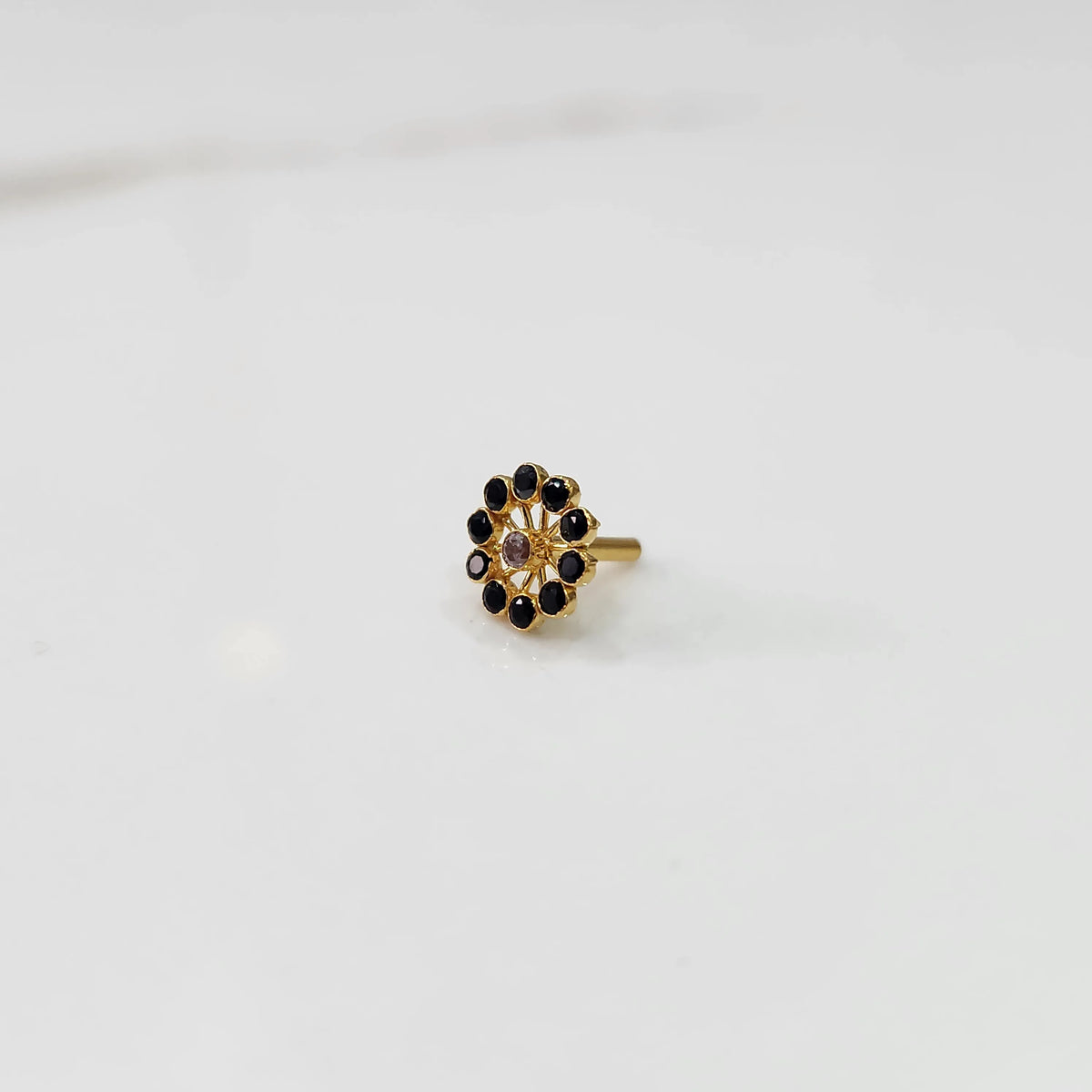 Large gold nose pin with black gemstone petals and center stone accent on white backgroundv