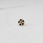 Front view of gold nose pin with black gemstone petals and clear center stone on white background