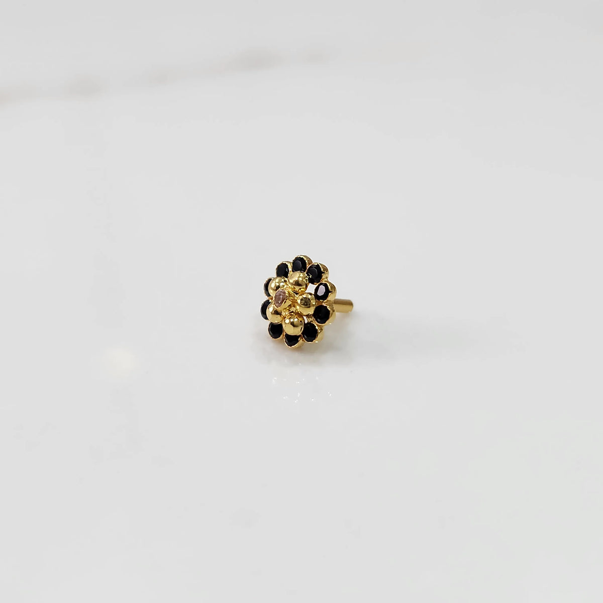 Traditional gold ring featuring black stones around a gold flower design