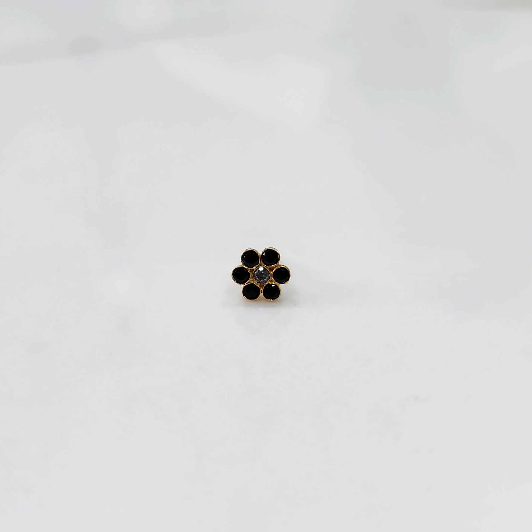 Gold flower stud earring with black stones and white center stone