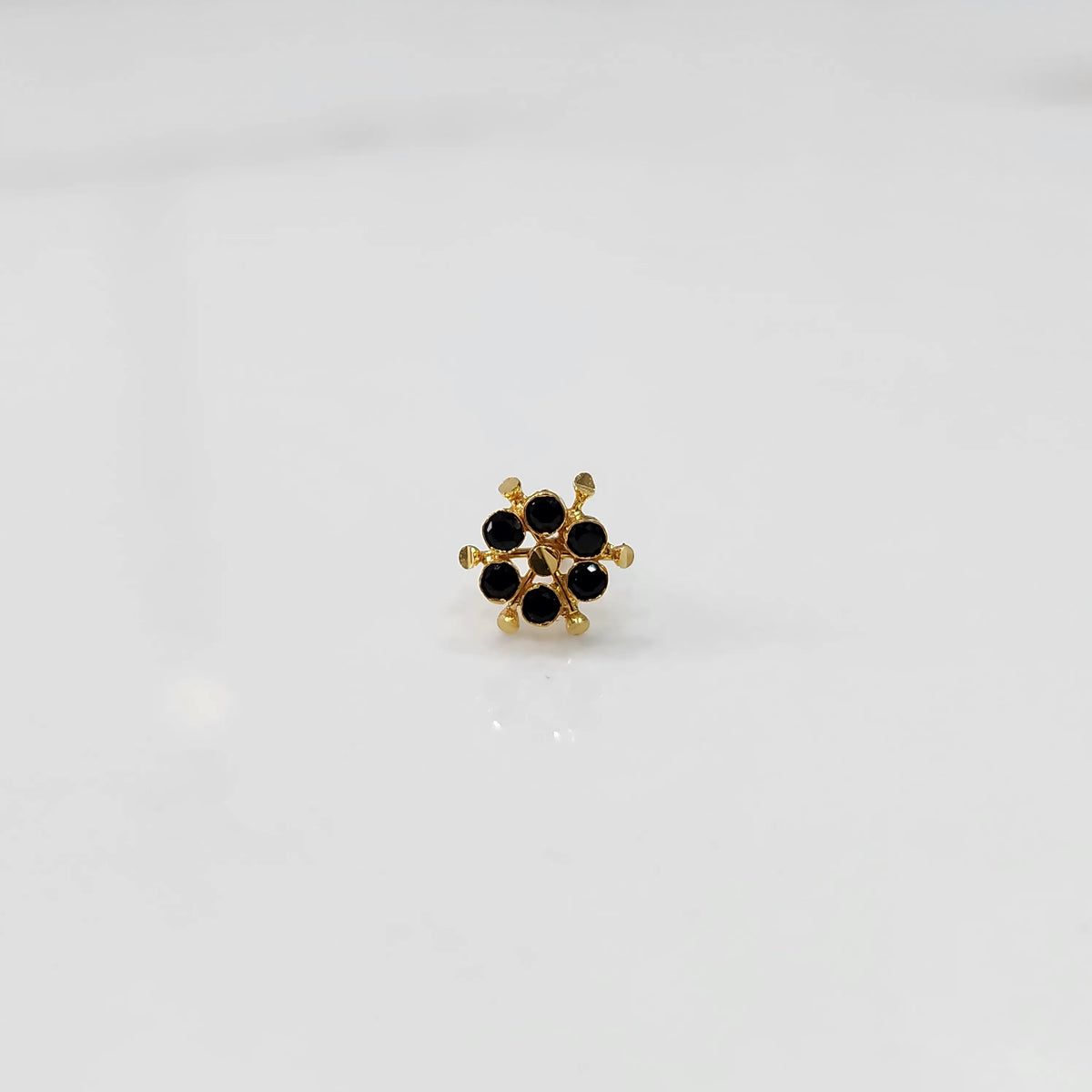 Close-up of gold statement ring with black gemstones in scattered dotted cluster design