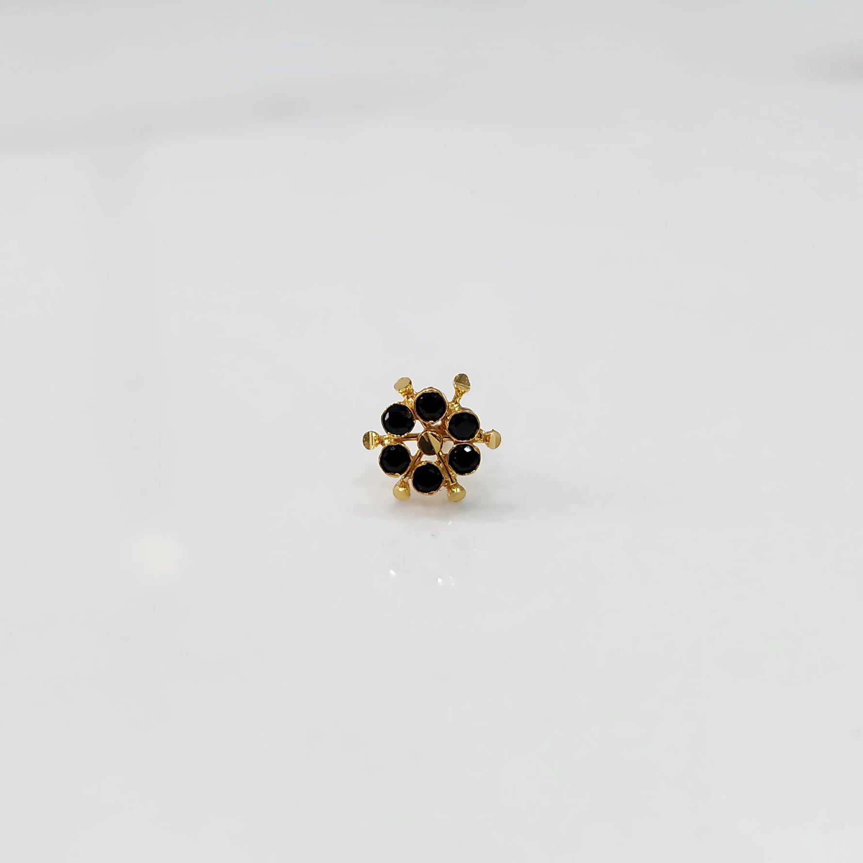 Close-up of gold statement ring with black gemstones in scattered dotted cluster design