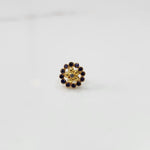 Close-up of flower-shaped gold nose pin with blue gemstone border
