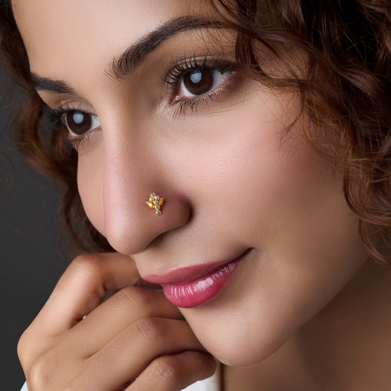 Woman wearing a floral gold nose pin with blue stone accent