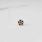 Gold nose pin with blue and white gemstone petals on white background